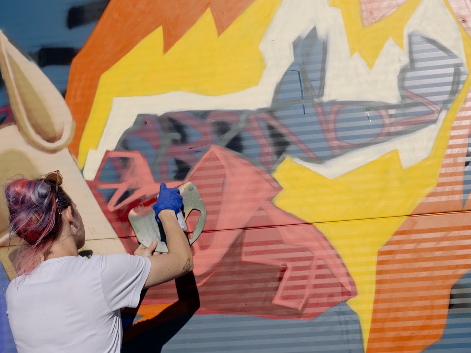 An artist working on a large mural, seen from below